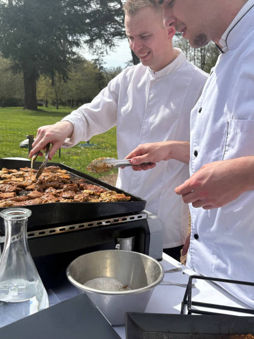 Deux membres de l’équipe traiteur Maison Grillon faisant griller des morceaux de viande